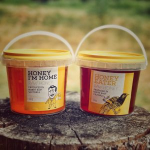 a 1 kg tub of pure honey sits on top of a log